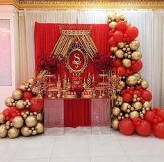 red and gold balloons are on display in front of a stage set for an event