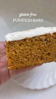 a hand holding a piece of pumpkin bars with cream cheese frosting