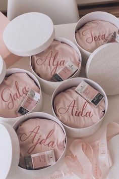 four personalized round boxes with pink satin ribbons in them and the names of each product