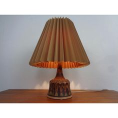 a lamp that is sitting on top of a wooden table next to a white wall