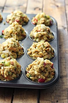 a muffin tin filled with cooked food on top of a wooden table