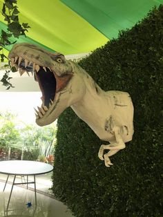 a fake t - rex in the middle of a room with green walls and plants