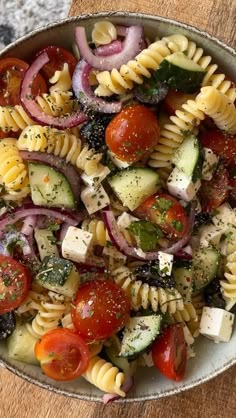 a pasta salad with tomatoes, cucumbers, onions and herbs in a bowl