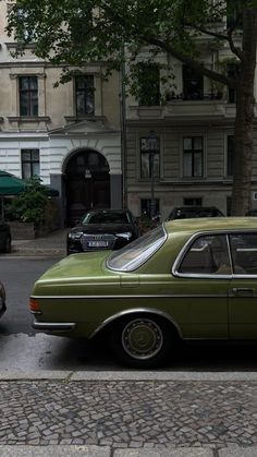 an old green car is parked on the street