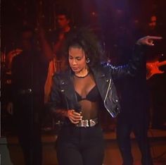 a woman in a black top and leather jacket on stage