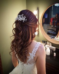 a woman in a wedding dress looking at herself in the mirror while getting her hair done