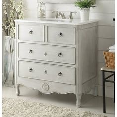 a white bathroom vanity with drawers and a mirror above it, next to a plant