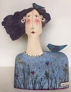 a ceramic sculpture of a woman with a bird on her shoulder and the head of a blue bird sitting on top of it