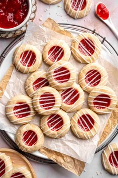 cookies with jelly on them are sitting on a plate next to some sauces and spoons