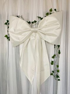 a white bow tied to the back of a chair with ivy growing on it's side