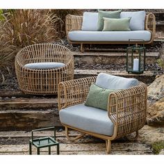 wicker furniture sitting on the steps in front of some plants and rocks with candles