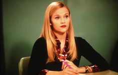 a woman sitting at a table with a pen in her hand