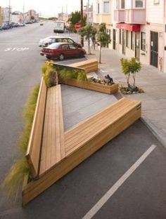 a car is parked on the street next to a wooden ramp with plants growing out of it