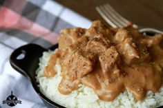 a close up of a plate of food with rice and meat in gravy