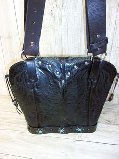 Infuse your look with a dose of Santa Fe style with this one-of-a-kind leather handbag. Hand-crafted from up-crafted cowboy boots and belts. Tote style with no pockets No two alike, signed and numbered Magnetic closure and metal concho detail Measures approximately 10"x12"x5" This exquisite leather bag is more than just a cowboy boot purse - it's a wearable work of art that celebrates the spirit of the American West. Perfect for the lady who wants to infuse her look with a dose of Southwestern s Western Leather Bags With Concho Details, Hand Tooled Leather Bags For Western-themed Events, Hand-tooled Leather Bags For Western-themed Events, Western Style Bags For Festivals, Western Leather Bags For Rodeo, Festival Leather Bag With Belt Included, Leather Festival Bag With Belt Included, Bohemian Leather Bag With Concho, Hand Tooled Leather Bags For Rodeo