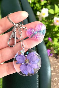 a hand holding a key chain with a flower in it