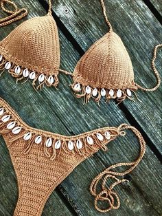 two bikinis with beads on them sitting on a wooden surface