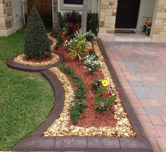 a house with landscaping in front of it and flowers on the ground next to it