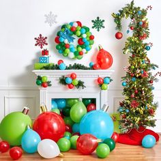 christmas decorations and balloons are on the floor in front of a fireplace with a tree