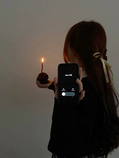 a woman holding up a cell phone with a lit candle in it's hand