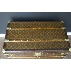 an old louis vuitton trunk sitting on top of a hard wood floor next to a wall