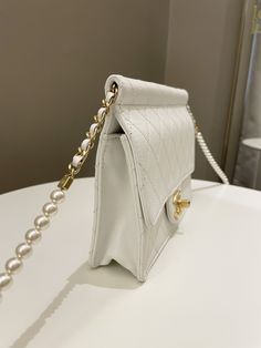 Chanel Pearl Chain Flap BagWhite Stiff Lambskin AGHWSize 24 x 17.5 x 7 cmChain drop 48 cm27 series9/10 Great (some faint interior stain and corners rub otherwise great)Includes dust bag and ity cardPrice now 3300 sgd 2515 usd CN5406-01 Chanel Pearl, Chanel Pearls, Gold Ounce, Carry All Bag, Pearl Chain, Black Tote Bag, Flap Bag, White Bag, Bottega Veneta