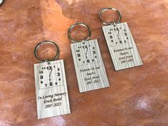 three personalized keychains with numbers and times on them sitting on a table