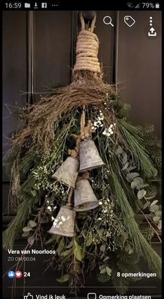 a bunch of bells that are hanging from a tree with greenery on it's sides