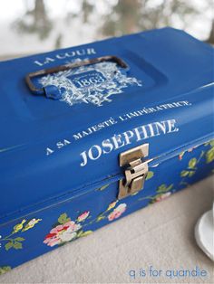 a blue suitcase sitting on top of a table next to a cup and saucer