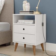 a white nightstand with two drawers and a lamp on top of it next to a bed