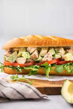 a chicken salad sandwich with lettuce, tomato and avocado