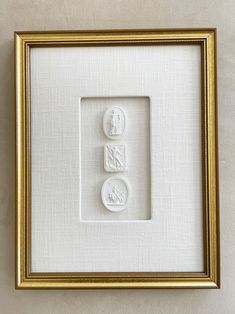 two white buttons in a gold frame on a wall