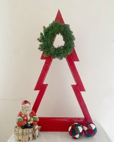 a christmas tree made out of red wood with a wreath on top and ornaments around it