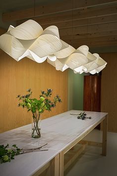 a vase with flowers sitting on top of a white table next to a wooden wall