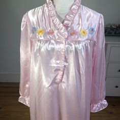 So pretty and sweet long sleeve pink satin vintage 70s house coat, robe, night gown. Embroidered flowers at the collar, ruffled trim at neck and sleeve hem. Styled at Saybury. Babydoll cozy loungewear. Looks like new with one small discoloration at sleeve hem. Medium. No holes. **all measurements are approximate and are done while laid flat** Shoulder to shoulder 17'' Underarm to underarm 23'' Waist 27'' Shoulder to hem 52'' Long Sleeve Satin Sleepwear For Spring, Long-sleeve Satin Nightgown For Sleepovers, Long Sleeve Satin Nightgown For Sleepovers, Satin Long Sleeve Nightgown For Sleepover, Feminine Long Sleeve Satin Sleepwear, Pink Long Sleeve Satin Robe, Vintage Pink Robe For Spring, Feminine Long Sleeve Home Robe, Feminine Long Sleeve Robe For Home