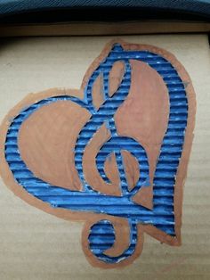 a piece of cardboard with blue and brown designs on it's side in the shape of a heart