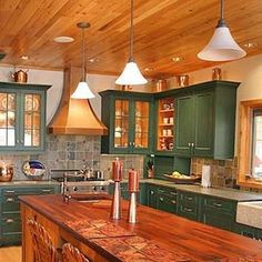 a large kitchen with green cabinets and wooden flooring is pictured in this image, there are lights hanging from the ceiling