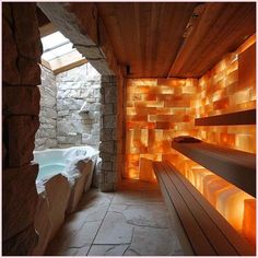 an indoor jacuzzi is lit up with orange lights and stone walls, as well as a skylight