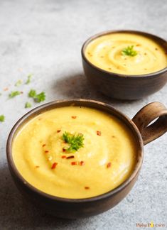 two brown bowls filled with soup on top of a table