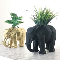 two elephant planters sitting next to each other on top of a wooden table with plants in them