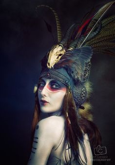 a woman with feathers on her head and makeup