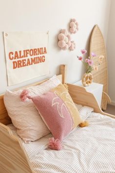 there is a bed with pillows on it and a sign that says california dreaming above the headboard