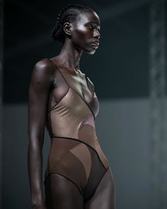 a woman in a bodysuit standing on a runway