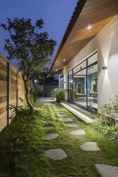 an outdoor walkway with stepping stones leading to the front door and side yard at night