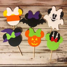 four mickey mouse cupcake toppers with bats and pumpkins on them, all decorated in different colors