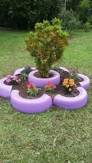 a purple tire planter sitting on top of a lush green field filled with flowers