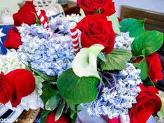 a bouquet of red roses and blue hydrangeas in a vase on a table