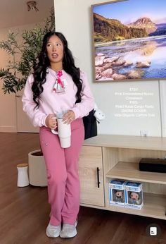 a woman standing in front of a tv holding a cup and looking at the camera