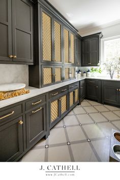 a large kitchen with black cabinets and white counter tops, gold trimmings on the doors