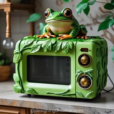 a frog sitting on top of a green microwave oven with leaves and vines painted on it